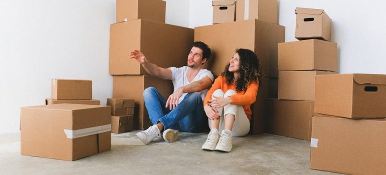 man and woman sitting among boxes after booking packing services Atlanta GA