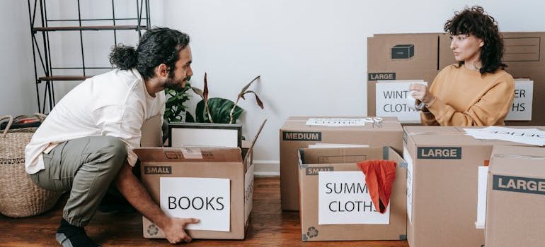 A Couple Packing Up Boxes With Labels