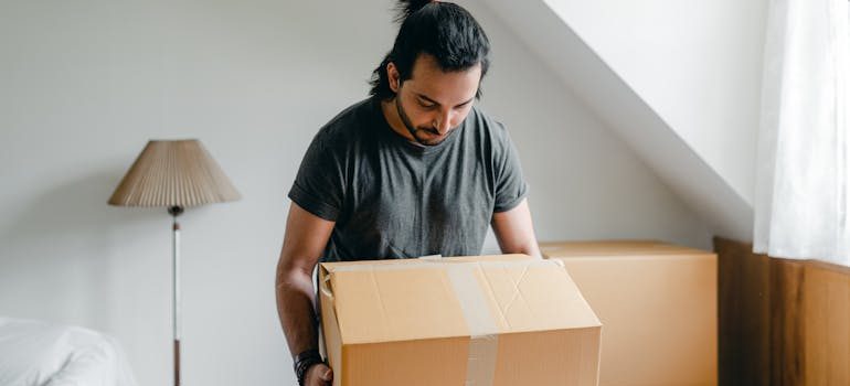 guy picking up cardboard box in house